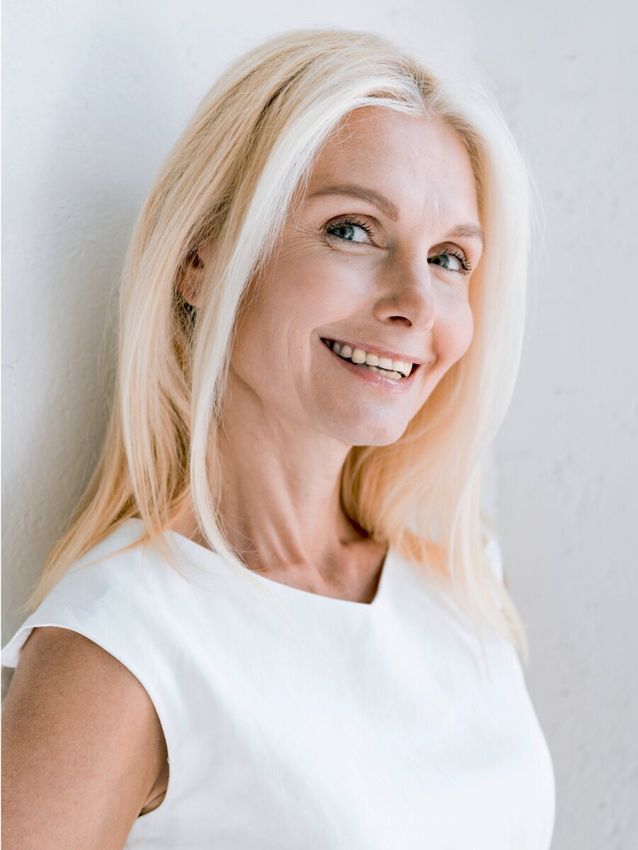 Smiling woman with long blonde hair, white top