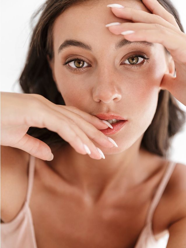 Model with natural makeup posing thoughtfully.