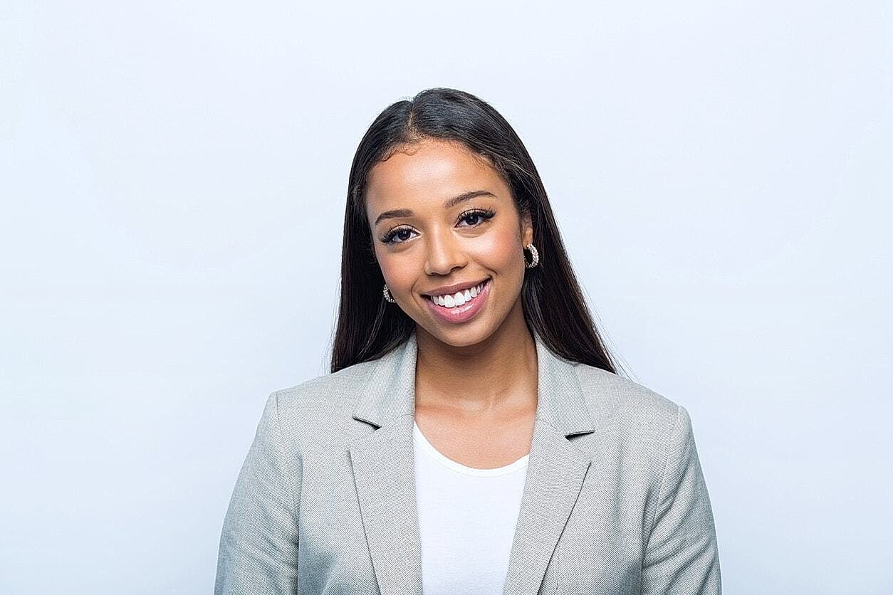 Smiling woman in a professional gray blazer.